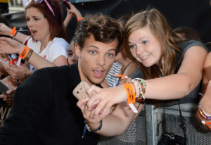 LONDON, ENGLAND - AUGUST 20: Singer Louis Tomlinson from One Direction poses with fans as he attends the "One Direction This Is Us" world premiere at the Empire Leicester Square on August 20, 2013 in London, England.