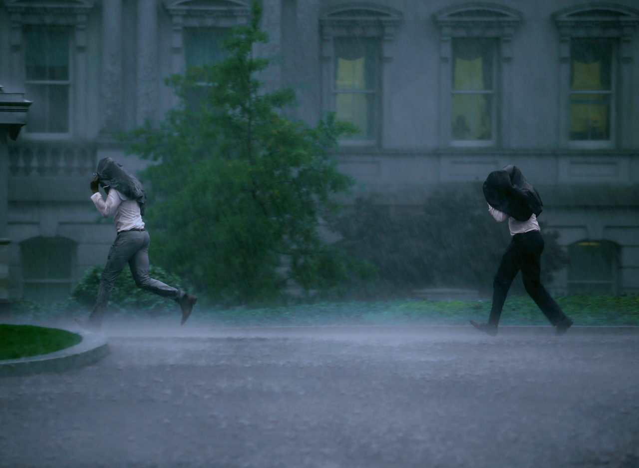 WASHINGTON, DC - OCTOBER 15: Two men run through the rain at the White House as a storm approaches on October 15, 2014 in Washington, DC. The Washington area was issued a tornado warning as a major storm front approached but was soon cancelled. (Photo by Mark Wilson/Getty Images)