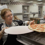 MIRAMAR, FL - NOVEMBER 18: Alina Bernardini places pizza pies into the oven during preparations for serving students lunch at Everglades High School on November 18, 2011 in Miramar, Florida. Monday evening the United States Congress passed a spending bill with a provision that would allow schools to count pizza as a vegetable. (Photo by Joe Raedle/Getty Images)