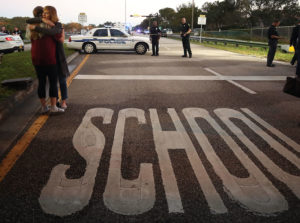 PARKLAND, FL - FEBRUARY 15: Kristi Gilroy (R), hugs a young woman at a police check point near the Marjory Stoneman Douglas High School where 17 people were killed by a gunman yesterday, on February 15, 2018 in Parkland, Florida. Police arrested the suspect after a short manhunt, and have identified him as 19-year-old former student Nikolas Cruz. (Photo by Mark Wilson/Getty Images)