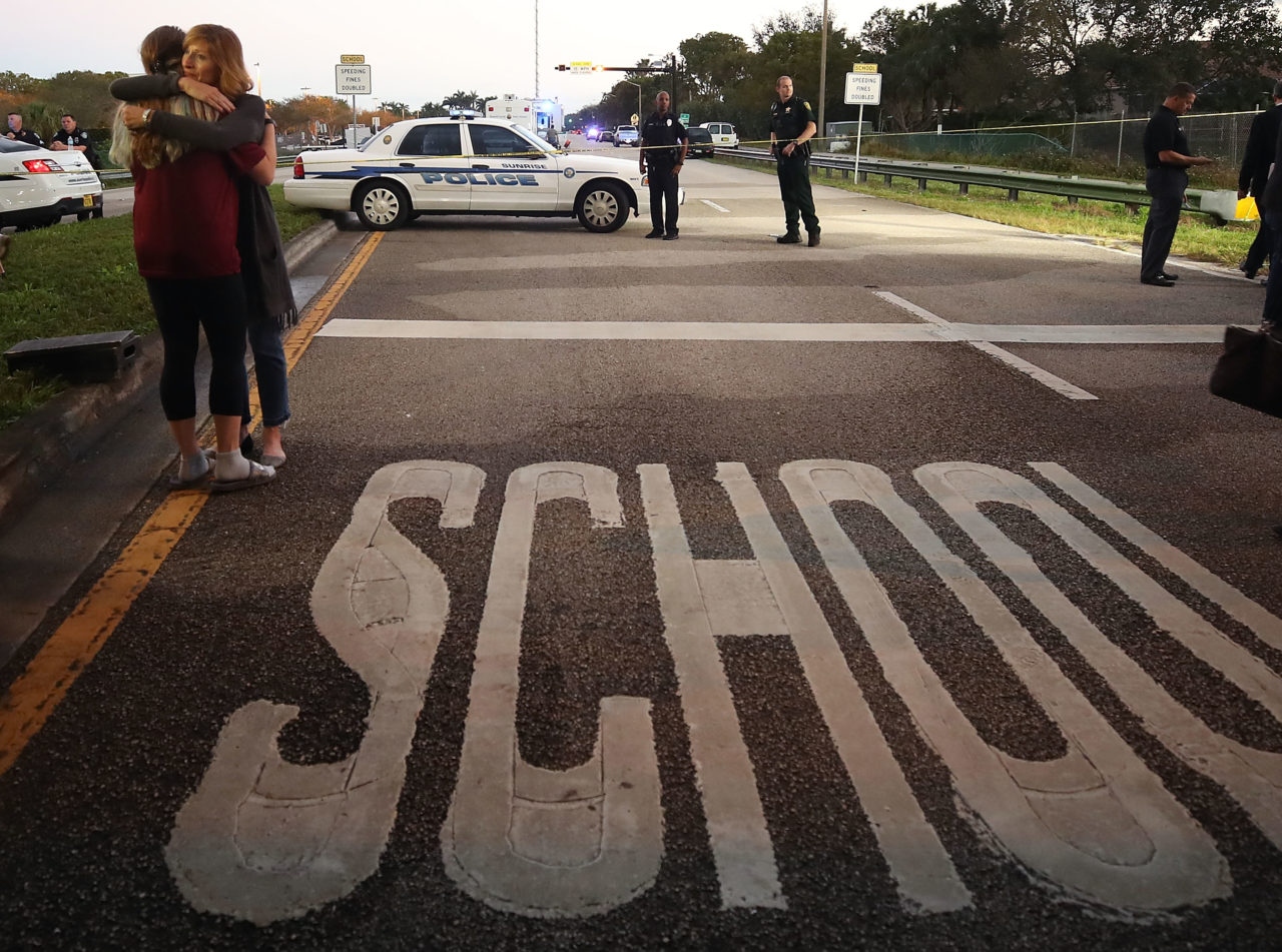 PARKLAND, FL - FEBRUARY 15: Kristi Gilroy (R), hugs a young woman at a police check point near the Marjory Stoneman Douglas High School where 17 people were killed by a gunman yesterday, on February 15, 2018 in Parkland, Florida. Police arrested the suspect after a short manhunt, and have identified him as 19-year-old former student Nikolas Cruz. (Photo by Mark Wilson/Getty Images)