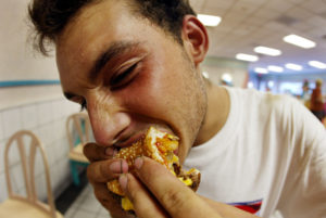MIAMI BEACH, FL - JULY 18: Jeff Baughman bites into his double cheeseburger with a Super Fries and a Super Coke on July 18, 2002 at a McDonalds in Miami Beach, Florida. The health effects of an American diet of super-sized fast foods are becoming apparent as increasing numbers of children and adults are being treated for obesity. Studies seem to point to the fact that many overweight children and adults get a large portion of their calories by consuming too many sodas and sweetened juices and beverages. Sweetened drinks + "super-sized" meals + the convenience of fast food + a decrease in physical activity = a recipe for obesity. (Photo by Joe Raedle/Getty Images)
