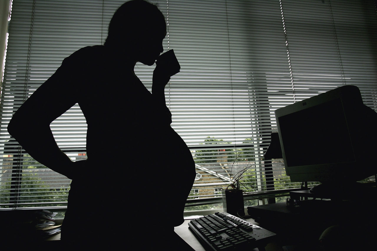 LONDON - JULY 18: In this photo illustration a pregnant woman is seen stood at the office work station on July 18, 2005 in London, England. Under plans to revise paid maternity leave, an exteneded period of six to nine months will be offered for maternity leave from 2007. (Photo illustration by Daniel Berehulak/Getty Images)