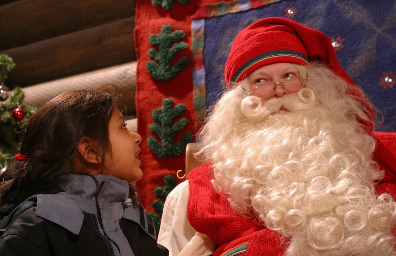 ROVANIEMI - DECEMBER 21: Kiasha Vekaria (6 years old) of Dartford, Kent, England, gazes at Santa Claus as she meets him in his office at Santa Claus village on the Arctic Circle near Rovaniemi, Finland on December 21, 2002. 480,000 people visit the centre each year, and 80 percent of them are adults. (Photo by Tony Lewis/Getty Images)