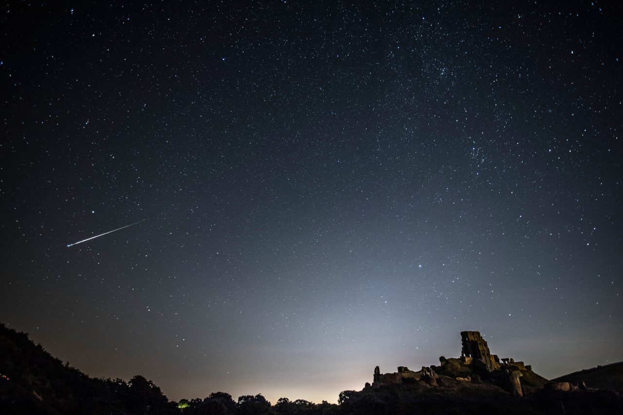 CORFE CASTLE, UNITED KINGDOM - AUGUST 12: A Perseid Meteor flashes across the night sky above Corfe Castle on August 12, 2016 in Corfe Castle, United Kingdom. The Perseids meteor shower occurs every year when the Earth passes through the cloud of debris left by Comet Swift-Tuttle, and appear to radiate from the constellation Perseus in the north eastern sky.